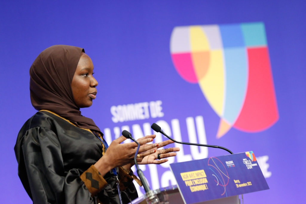 Image décorative d'une jeune femme parlant dans un micro lors du Sommet de l'inclusion économique.